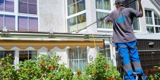 Einen guten Fensterputzer finden in Berlin / Brandenburg: Ein Mitarbeiter des Reinigungs-Service Oldenburg steht auf einer Leiter und putzt ein Wintergartendach mithilfe einer Teleskopstange und Osmose-Wasser