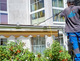 Einen guten Fensterputzer finden in Berlin / Brandenburg: Ein Mitarbeiter des Reinigungs-Service Oldenburg steht auf einer Leiter und putzt ein Wintergartendach mithilfe einer Teleskopstange und Osmose-Wasser